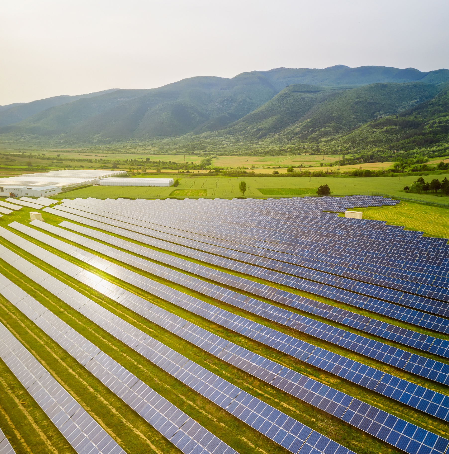 Utility-scale solar array at a rural site backed by distant mountains